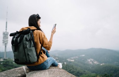 Sırt çantalı kadın gezginin cep telefonuyla e-posta gönderdiğini gezintide iyi internet bağlantısı olduğunu sosyal ağları kontrol eden kadın blogcu hedef belirleme