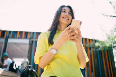 Gülümseyen milenyum kıyafetleri içinde cep telefonu tutan 4G 'ye bağlı hippi kız mesajlar gönderiyor, 20' li yaşlarda genç kadın nüfuzlu biri cep telefonuyla şehirde iletişim kuruyor.