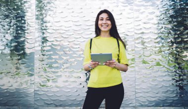 Neşeli Asyalı bir kadının yarım boy portresi dışarıda duruyor 4G bağlantısı olan modern dijital tableti tutuyor, kadın milenyum öğrencisi touchpad 'de online eğitimin tadını çıkarıyor kameraya bakıyor.