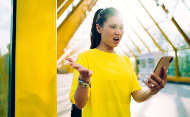 Kızgın duygusal hippi kız dışarıda duran sosyal ağlardan gelen haberlere kızgın, cep telefonuyla bağıran Asyalı genç kadın kablosuz bağlantıda sorun yaşıyor.