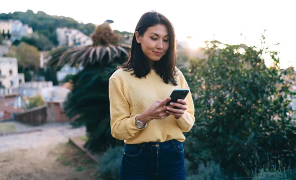 Beautiful Asian blogger tracking mobile location gps during touristic sightseeing in village, attractive generation Z connecting to 4g for chatting and networking via smartphone application