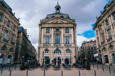 Fransa 'nın Bordeaux şehrinde bulutlu gökyüzünün altında eski binaların altından süsleri ve kaldırım kafesi