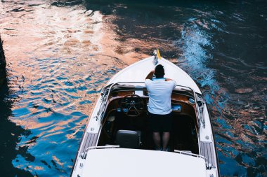 Venedik 'e yelken açarken pahalı bir teknede dinlenen ve İtalya' daki bir sonraki durağı düşünen isimsiz bir erkeğin tepesinden.