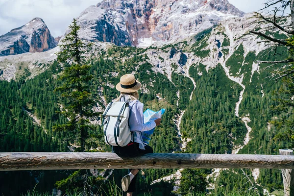 バックパック付きの若い女性のバックパックフェンスに座って Karersee湖への山の尾根を旅しながら紙の地図を調べます — ストック写真