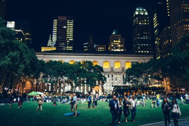 New York 'taki yüksek gökdelenlere karşı gece vakti eski binanın yakınında yürüyen tanınmayan insanların yan görüntüsü