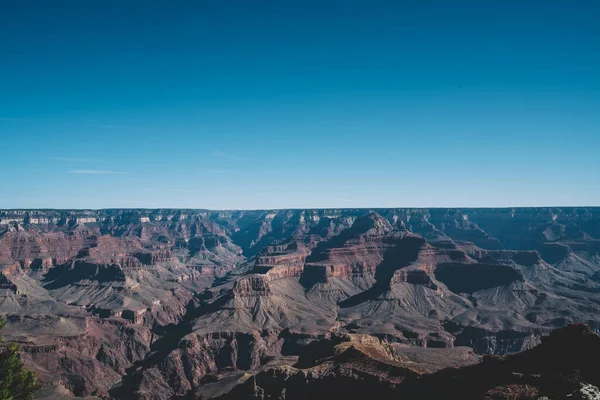 Picturesque aerial landscape of rock formations with various geological layers in Grand Canyon National Park against cloudless blue sky in sunny weather