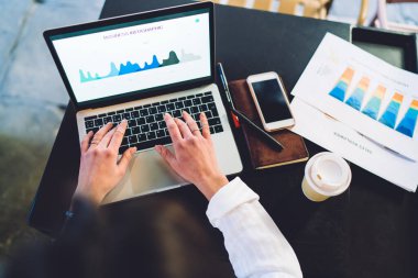 Tahta masada oturan ve kafede otururken dizüstü bilgisayarla uzaktan kumandalı bir proje üzerinde çalışan isimsiz kadın serbest yazar.