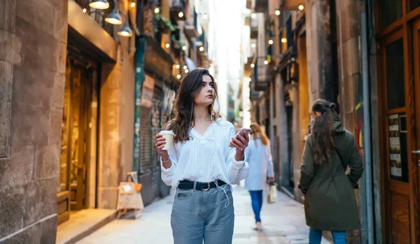 Pondering Hipster Girl Earphones Holding Coffee Hand Standing Ancient Street — Stock Photo, Image