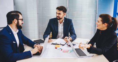 Çalışma sırasında bankacılık teknolojisini tartışan deneyimli çalışanlardan oluşan bir grup modern cihazlarla masaüstü beyin fırtınası yapıyorlar, kendine güvenen meslektaşlar ofis işbirliği sırasında takım çalışması ve beyin fırtınası yapıyorlar.