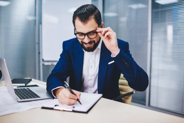 Görme koruma iş planı için optik göz giyimi konusunda mutlu Kafkas erkek yönetici, modern dizüstü bilgisayarla masa başında çalışan başarılı profesyonel uzman 30 'lu yaşlarda