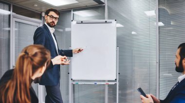 Erkek ve kadın çalışanlar, yönetim kurulu toplantısında gelir diyagramını analiz ederken başarılı meslektaşlar, Flipchart 'ta verimlilik eğitimi sunumu sırasında grafik grafiklerini tartışıyorlar.