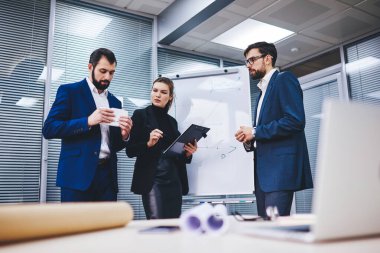 Kendine güvenen erkek ve kadın çalışanlar ofis internet bağlantısını finansal web sitesini taramak ve takas haberlerini modern dokunmatik ped ile kontrol etmek için kullanıyorlar.