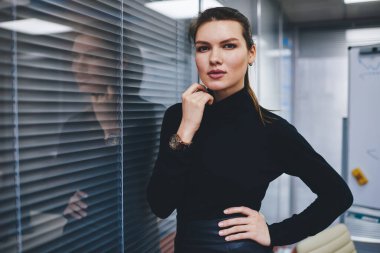 Çalışma sırasında ofis içinde poz veren çekici kadın yöneticinin yarı boy portresi, resmi giyinmiş beyaz girişimci 30 yaşında atölye firmasında kameraya bakıyor.