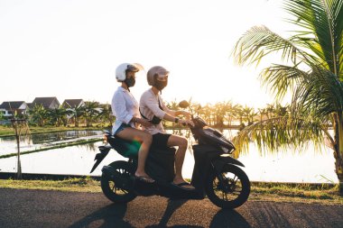 Maskeli ve kasklı, motosiklet süren ve yaz tatilini birlikte geçirirken sıcak ülkede takılan isimsiz bir çiftin yan görüntüsü.