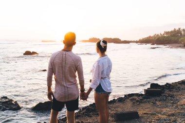 Kimliği belirsiz bir adam ve kadının el ele tutuşup tropikal bir tatil köyünde el ele tutuşup birlikte vakit geçirmelerinin arka planı.