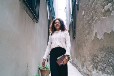 Neşeli, kıvırcık, esmer, hippi kız boş zamanların tadını çıkarıyor ve şehir ortamlarında yürüyor. Afro-Amerikan kadın modaya uygun giyinmiş, boş zamanlardan ve şehirdeki yerleri keşfetmekten memnun.