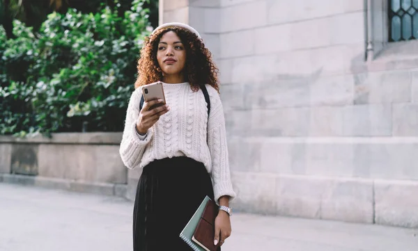 Pensiv Trendigt Klädd Afrikansk Amerikansk Kvinna Som Håller Mobiltelefon Tittar — Stockfoto