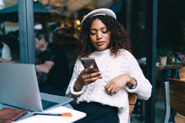 沉思的深色皮肤千年嬉皮士女孩看了智能手机上的视频浏览网页 美丽的非洲裔美国女性自由职业者用银行应用软件在网上支付和交易 — 图库照片