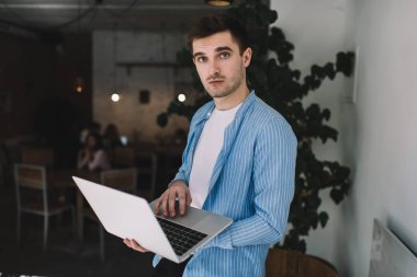 Modern netbook 'u elinde tutan Kafkas yazılım geliştiricisinin yarım boy portresi web projesiyle ilgili, bilgisayarlı yetenekli milenyum programcısı kameraya bakıyor.