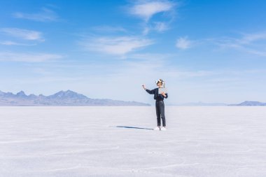 Doğada yeni bir proje tasarlarken, kurumuş yüzey üzerinde duran, VR gözlüklü, tanınmayan bir kadının tüm vücudu.