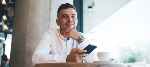 Usmívající Mladý Muž Formálním Oblečení Pomocí Smartphone Zatímco Těší Šálek — Stock fotografie