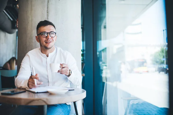 Jovem Alegre Roupa Casual Óculos Desfrutando Xícara Café Enquanto Trabalhava — Fotografia de Stock