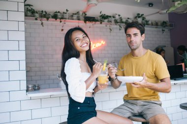Gündüz vakti modern kafede romantik bir buluşmada şık giyinen ve birlikte yemek ve içeceklerin tadını çıkaran mutlu çift.