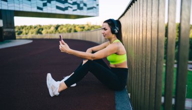 Aktif görevde olan beyaz kadın sporcu, sabah antrenmanından sonra selfie çekmek için akıllı telefon kamerası kullanıyor. 20 'li yaşlarda güzel bir kadın internet sitesinde paylaşmak üzere cep telefonundan video çekiyor.