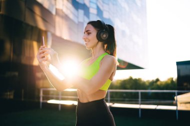 Neşeli kadın spor blogcusu sosyal takipçilerle açık hava sporları hakkında konuştuğu için çevrimiçi video konferansı yapıyor ve internet üzerinde etkili bilgiler veriyor, kulaklıklı mutlu bir kadın selfie çekiyor.