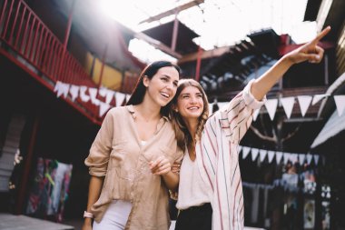 Şık giyinmiş genç beyaz kadınlar dünyayı keşfetmek için birlikte geziyorlar şehir manzarasını tartışıyorlar, şehir merkezinde mutlu 20 'li yaşlarda arkadaşlar sosyalleşiyorlar.