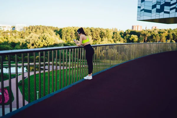 Frau Sportbekleidung Mit Turnschuhen Und Kopfhörern Steht Auf Der Terrasse — Stockfoto