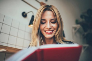 Mutlu beyaz kız öğrenci, edebiyat kitaplarını okumak için boş zamanlarının keyfini çıkarıyor. Pozitif entrikalı, neşeli hippi kız elinde eğitim kitabı tutuyor ve notları kontrol ederken gülümsüyor.