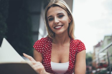 Eğitimle ilgili ders kitabını tutan samimi kadın okuyucunun portresi ve şehrin kenar mahallelerinde poz vermek, boş zamanlarında kameraya gülümseyen mükemmel dişleri olan zengin bir kadın.