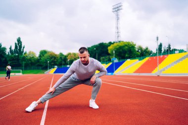 Spor kıyafetleri giymiş, spor giyinen ve antrenmandan önce koşu pistine atlayan tüm vücudu formda erkek sporcularla dolu.