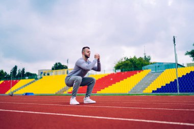 Aktif giyinen, sabah antrenmanlarında çömelme ve zayıflama konusunda kararlı, 20 'li yaşlarda yakışıklı bir erkek sağlıklı yaşam tarzı ve esnekliğini korumak için egzersiz yapmaya odaklanmış.