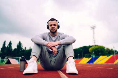 Stadyum dinledikten sonra sağlıklı yaşam tarzını koruyan yakışıklı beyaz erkek portresi. 20 'li yaşlarda yakışıklı bir adam aksesuar ve müzik listesinden memnun bir şekilde kameraya bakıyor.