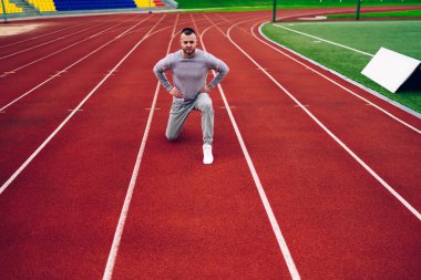 Kafkasyalı hippi adamın portresi. Eğitimli bacaklar için çömelmiş zayıflama ve kilo verme kasları, ciddi yakışıklı sporcu sabah koşusundan önce ısınma egzersizleri yapıyor.