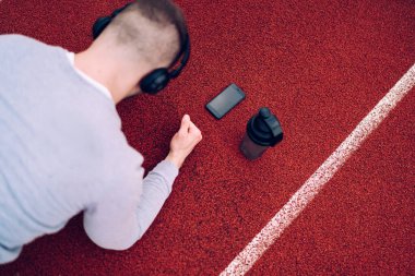 Beyaz adamın kalas eğitimi esnekliği ve vücut esnekliği ile müzik dinlemek için modern kulaklıklar kullanarak ayakta durması, bluetooth ile kulaklığa bağlı cep telefonuna seçici odaklanma