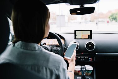 Beyaz tişörtlü, yüzü olmayan genç bir kadının, direksiyonda rahat bir şekilde otururken akıllı telefondan sesli mesaj kaydetmesinin arka planı.