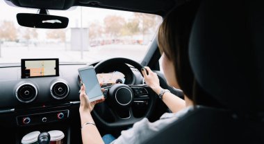 Siyah saçlı, yüzü olmayan genç bir kadının modern bir araç kullanması ve sabahları mobil uygulama kullanarak yön bulması.