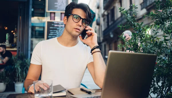 Freelancer Inteligente Sério Óculos Fazendo Telefonema Enquanto Está Sentado Mesa — Fotografia de Stock