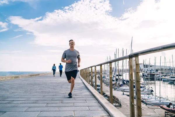 Eşofmanlı Mutlu Genç Erkek Koşucu Kıyı Şeridi Yakınlarındaki Kardiyo Çalışmasında — Stok fotoğraf