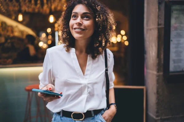 Optimista Etnikai Néz Félre Miközben Böngészi Interneten Mobiltelefon Mosolyog Nyaralás — Stock Fotó