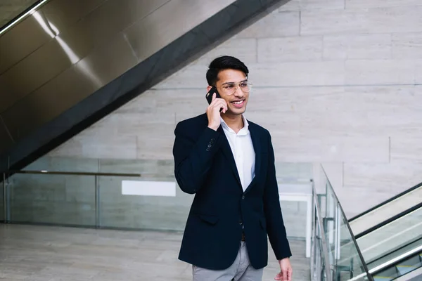 Uśmiechnięty Młody Etniczny Biznesmen Okularach Garniturze Rozmawiający Przez Telefon Komórkowy — Zdjęcie stockowe