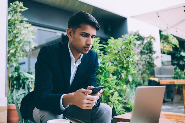 Homem Étnico Jovem Concentrado Terno Formal Com Smartphone Sentado Terraço — Fotografia de Stock