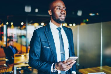 Afro-Amerikalı düşünceli erkek girişimci akıllı telefondan başvuru rezervasyonu üzerinde kafa yoruyor resmi olarak düşünceli iş adamı ofis işyerindeki 4G bağlantısını kullanarak cep telefonu taşıyor.