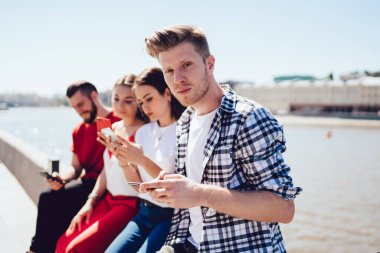 Bulanık arkadaşları internet yayınını tartışırken ve medya içeriğini akıllı telefon cihazlarıyla paylaşırken, kafkasyalı dijital cep telefonlu adam portresi