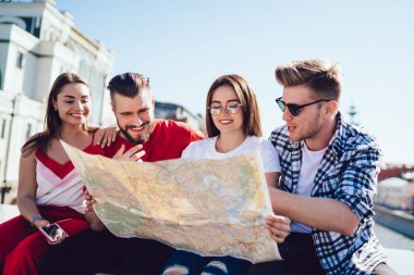 Bir grup neşeli turist arama güzergahı için seyahat haritası kullanıyor ve yaz tatillerinde şehri keşfediyorlar, oryantasyon kağıdıyla mutlu Kafkasyalı hipster adamlar komik yolculukları tartışıyor.