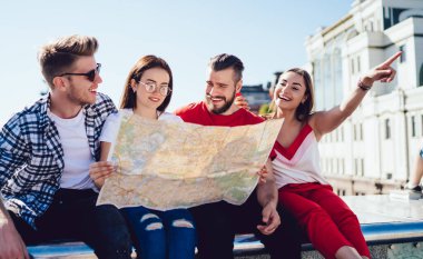 Bir grup neşeli turist arama güzergahı için seyahat haritası kullanıyor ve yaz tatillerinde şehri keşfediyorlar, oryantasyon kağıdıyla mutlu Kafkasyalı hipster adamlar komik yolculukları tartışıyor.