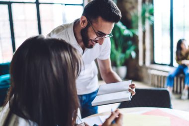 İyimser sakallı erkek çalışan meslektaşından tavsiye istiyor ve kafede yeni bir proje üzerinde çalışırken not defterine bakıyor.